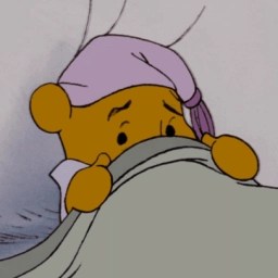 Winnie de Poeh in bed die zichzelf bedekt met een deken