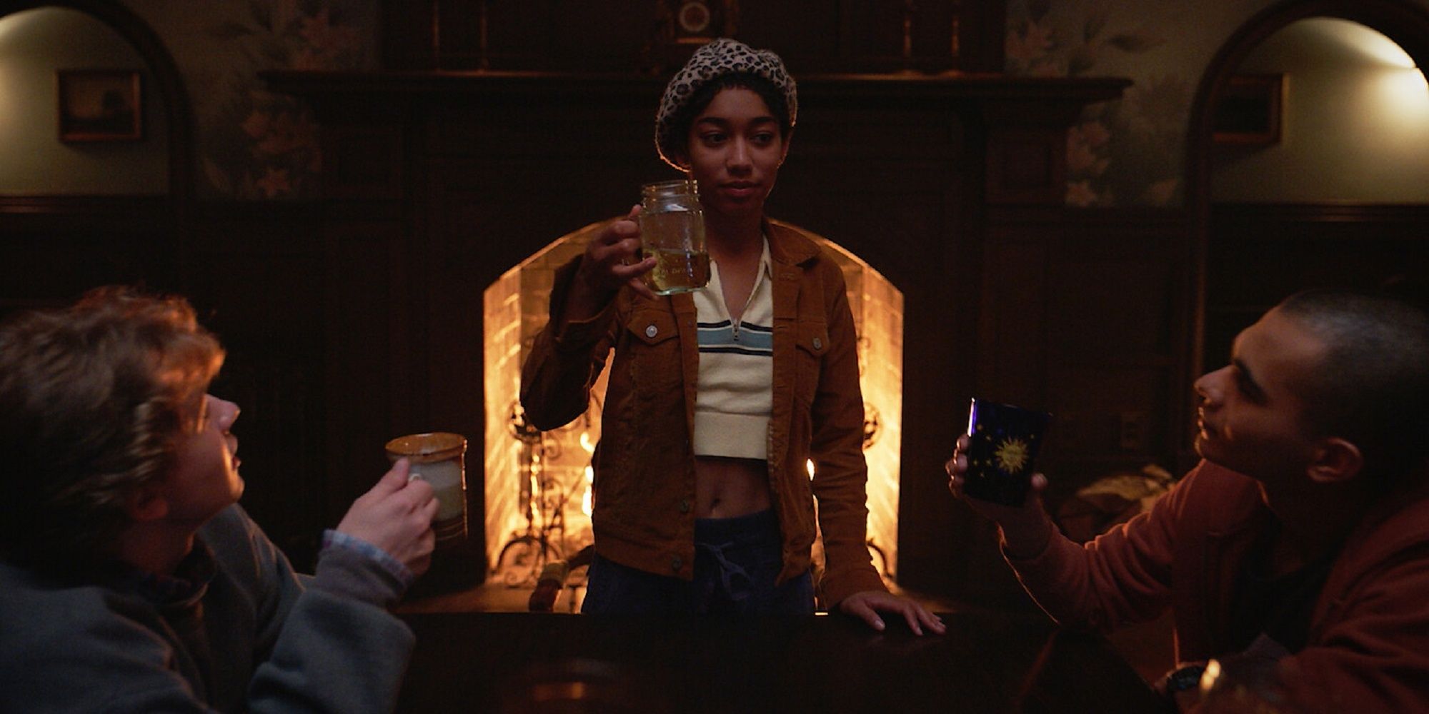 Het personage van Iman Benson houdt haar glas omhoog om te proosten op de drankjes van haar vrienden in 'The Midnight Club'.