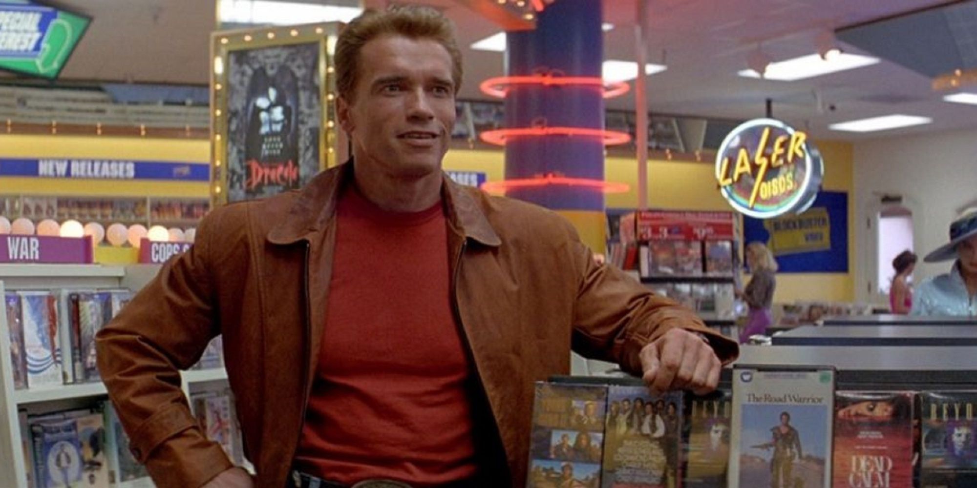 Arnold Schwarzenegger staat naast zijn nep-terminator 2-poster in Last Action Hero.